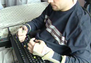 Chris using a pair of typing sticks at the computer