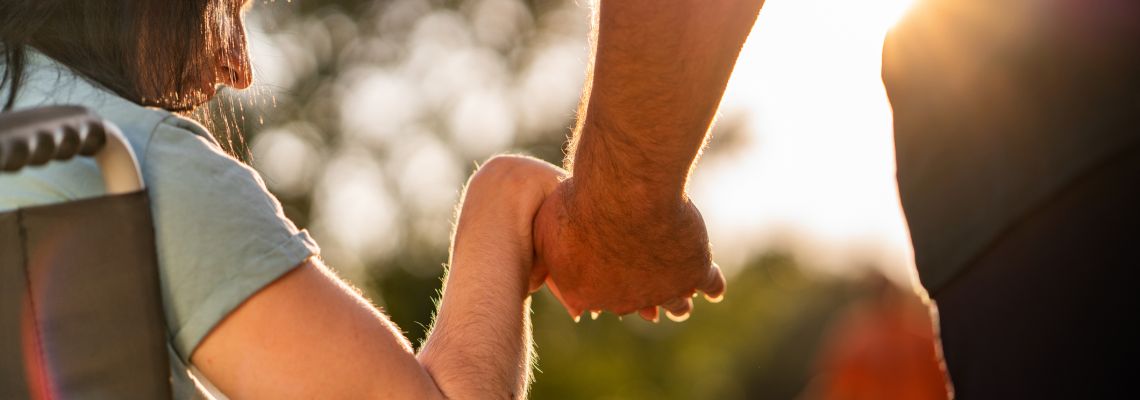 Close up women on a wheel chair holding mens hand