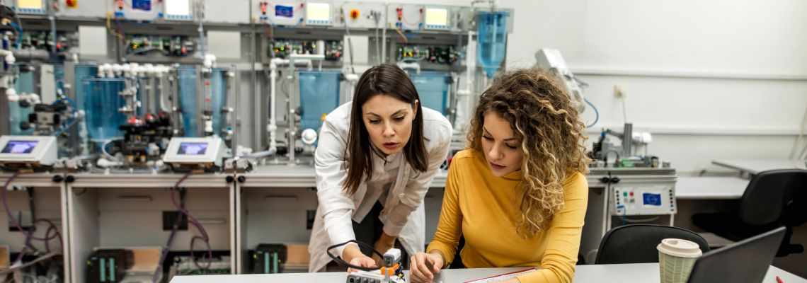 Two female graduates of ABET accredited online schools working on a robotics project