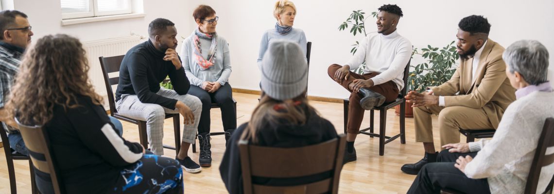 Group of people sitting in a circle for  mental health support in a modern mental health facility