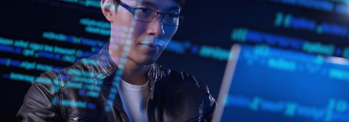 Asian man computer engineer programmer typing code hacking using computer with futuristic computer code, internet digital technology concept. Cybersecurity professional looking at code on a computer.