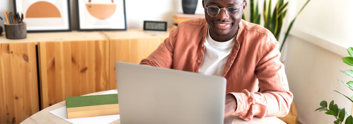 Happy male online HBCU student studying at home using laptop.