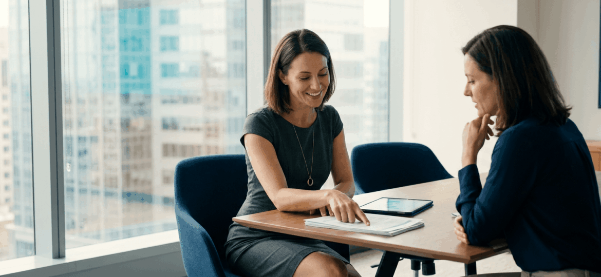 Operations manager leading a discussion over printed reports in a modern office.