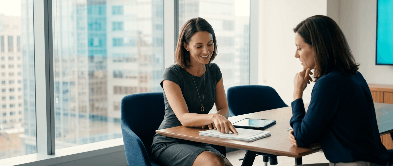 Operations manager leading a discussion over printed reports in a modern office.
