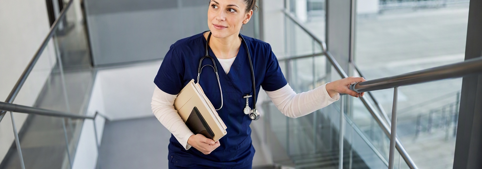 Adult nursing student reviewing online coursework on a digital tablet in a bright room