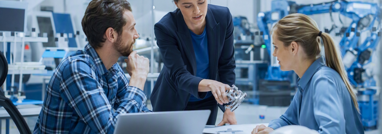 Two adults discussing options for an online master's in engineering management in a bright office